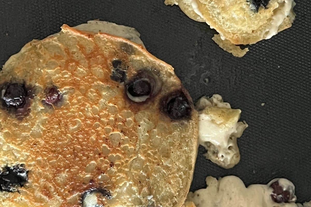 Blueberry pancakes cooking on a griddle. 