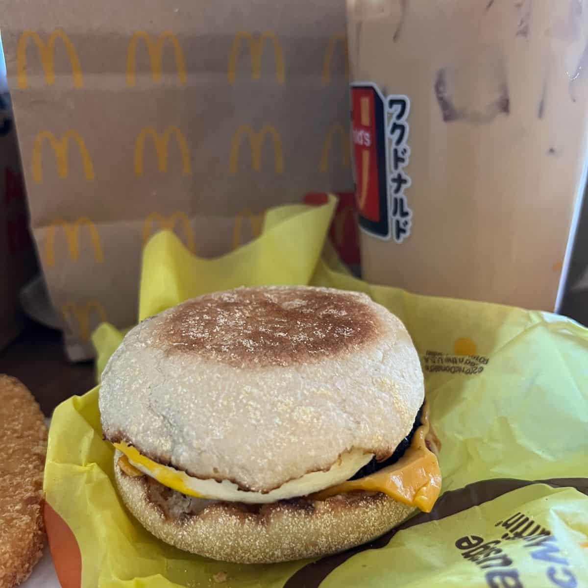 An egg mcmuffin and coffee from Mcdonald's, in front of a Mcdonald's bag. 