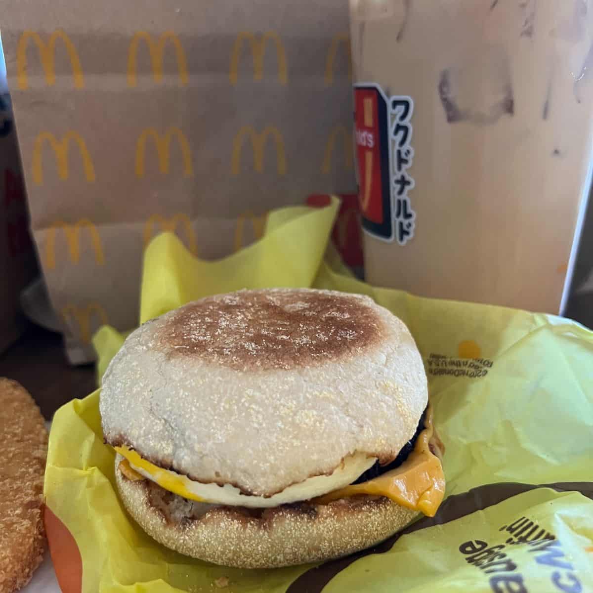 An egg mcmuffin and coffee from Mcdonald's, in front of a Mcdonald's bag.