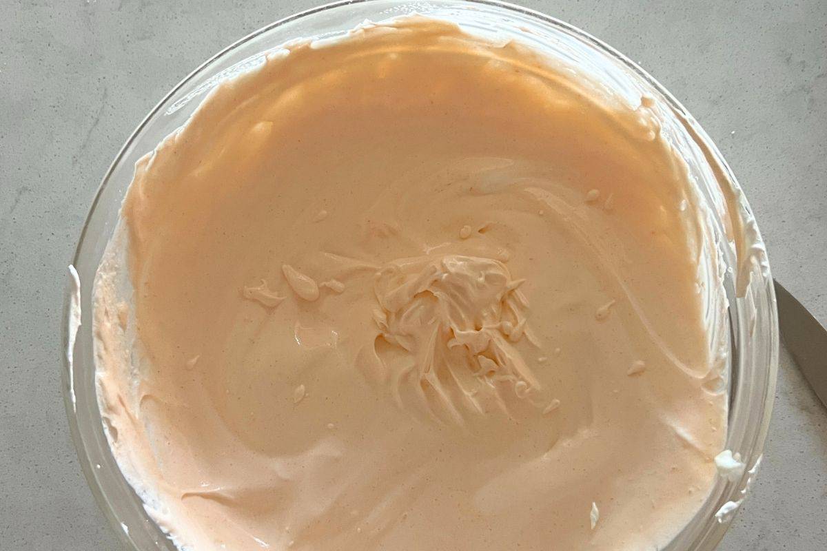 Cool Whip, yogurt, and orange jello combined together in a bowl.