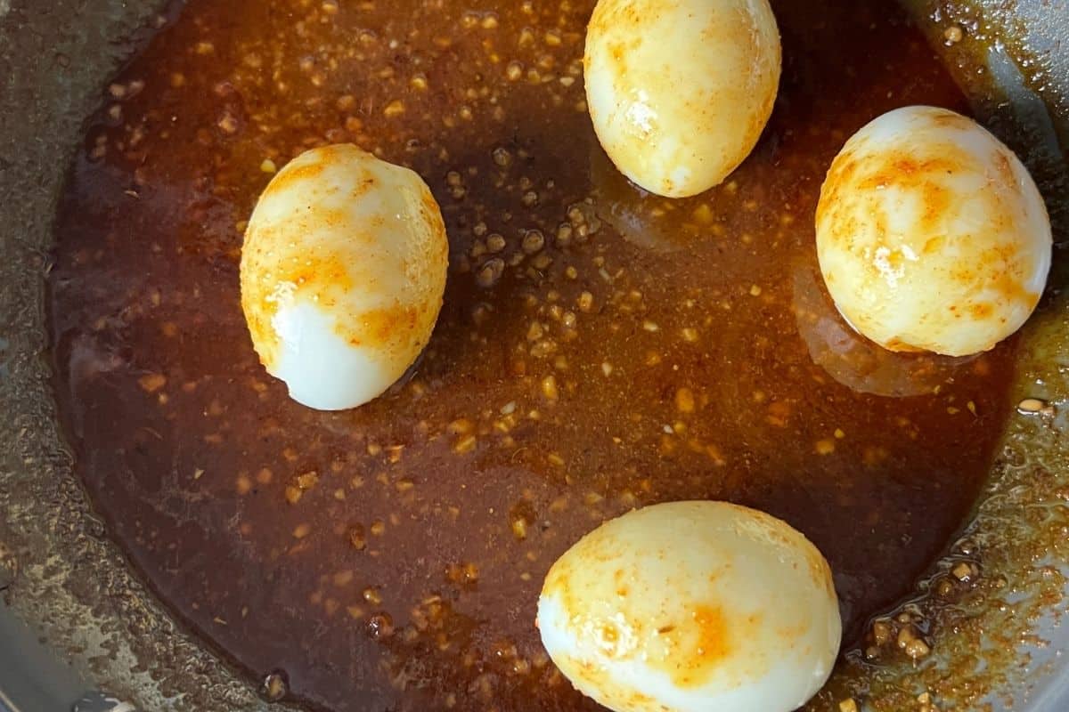 Hard boiled eggs cooking with spicy red sauce. 
