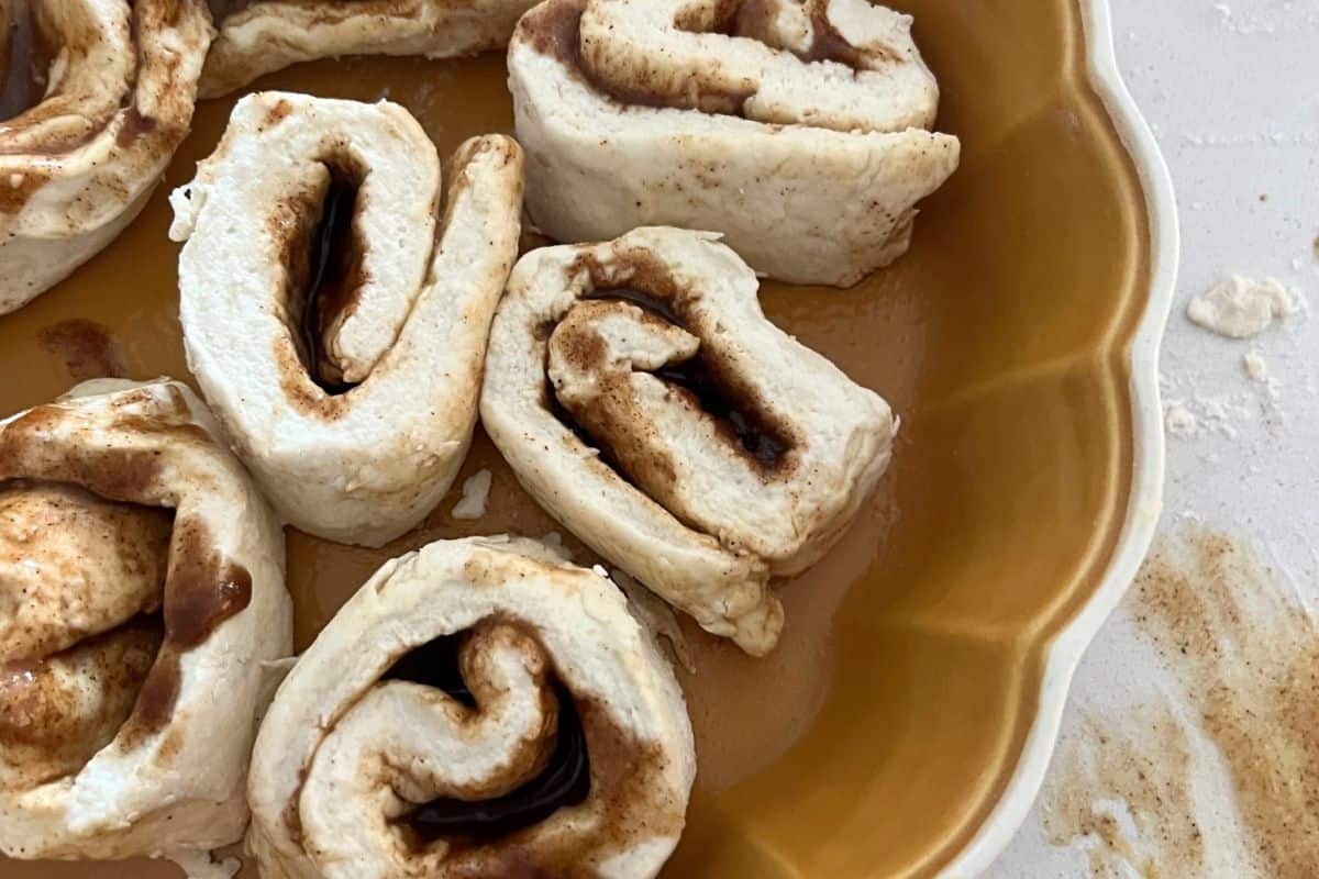 Cinnamon rolls spread out evenly and cut in a pie plate dish. 