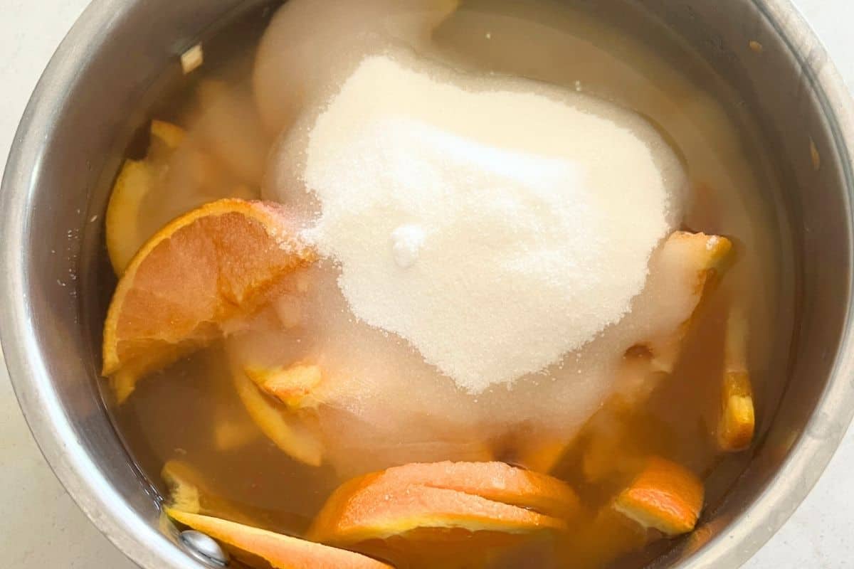 Sugar, oranges, and water in a pot.