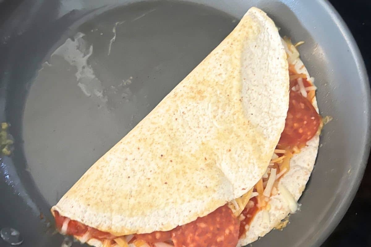 Folded quesadilla in a skillet.
