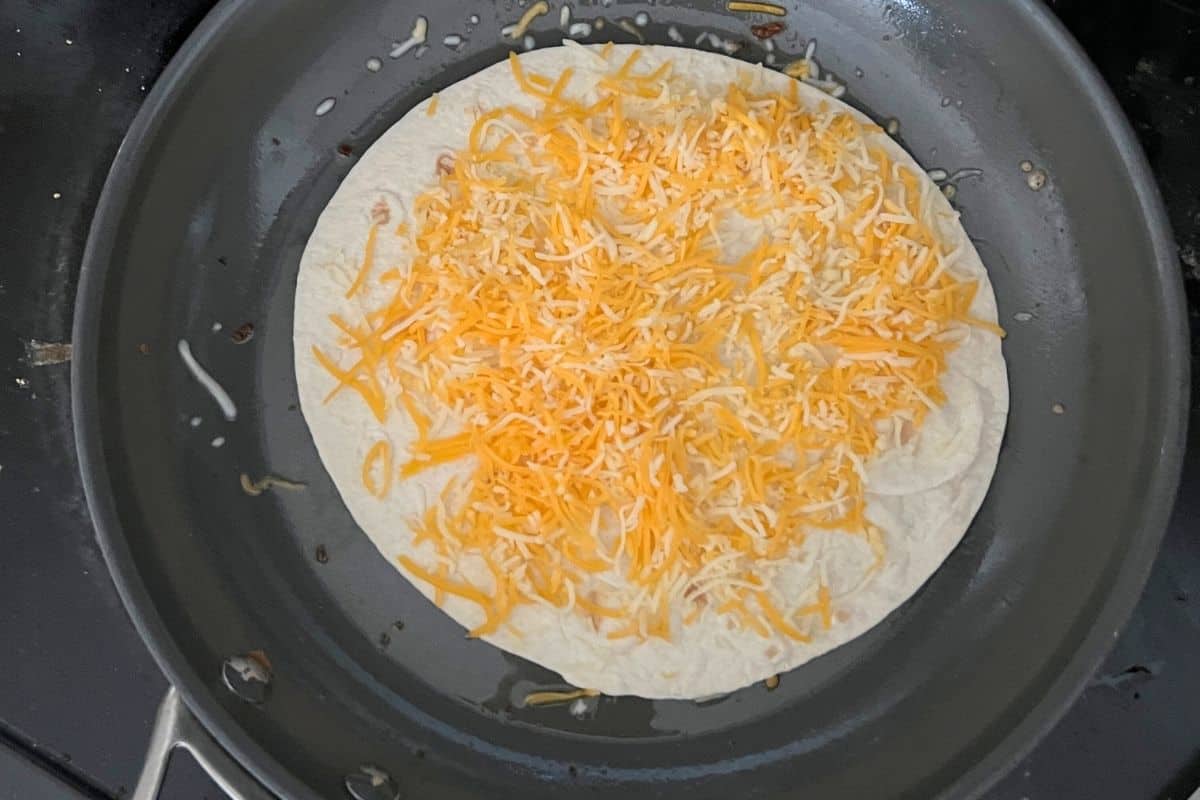 Cheese melting on a tortilla in a pan. 