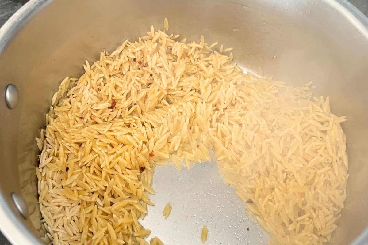 Orzo pasta cooking in a pan.