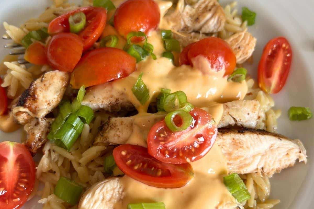 Cooked griddle chicken smothered in queso sauce and topped with tomatoes and green onionos.
