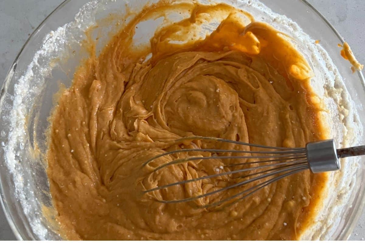Canned pumpkin and cake mix added to a bowl.