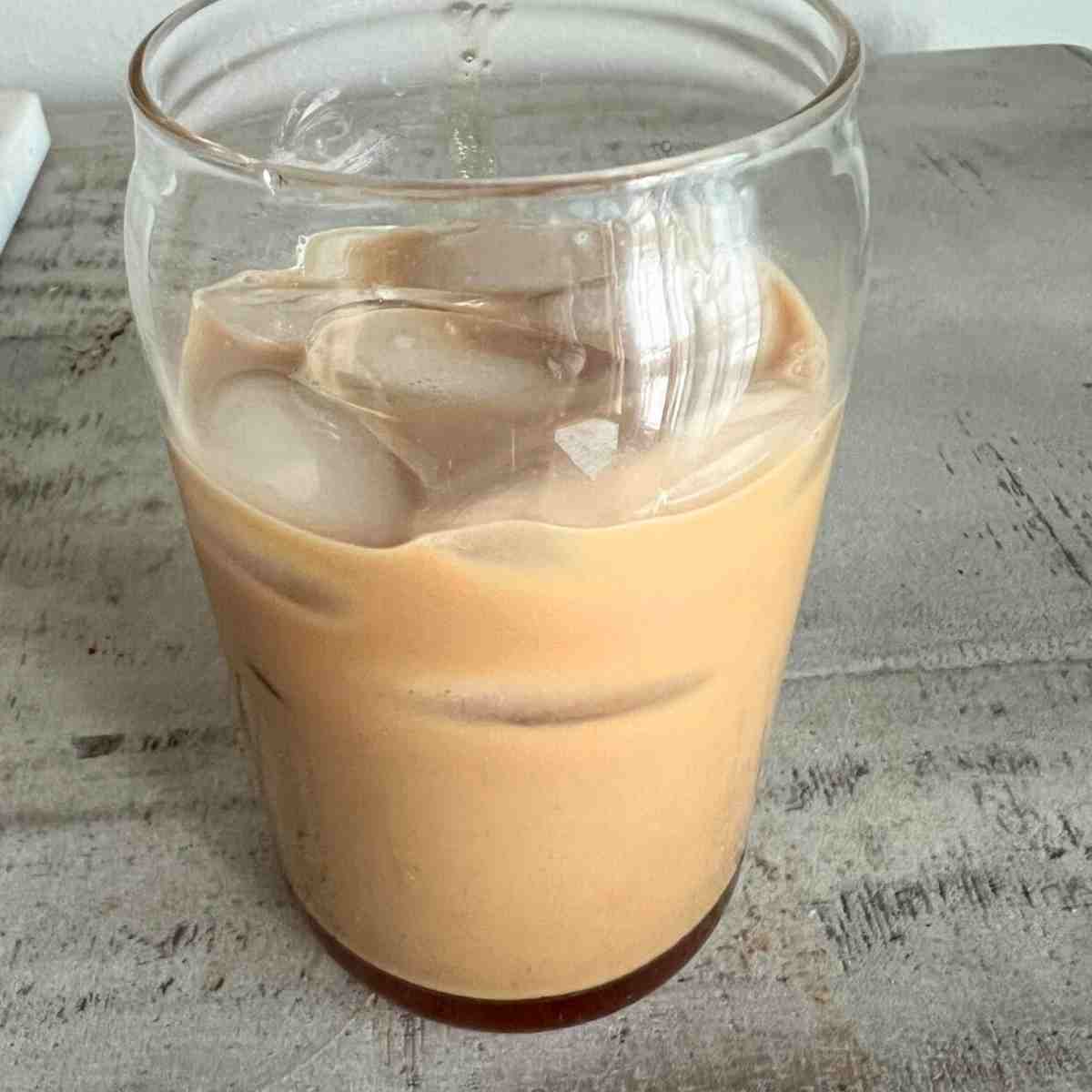 Teddy graham latte with ice in a clear glass.