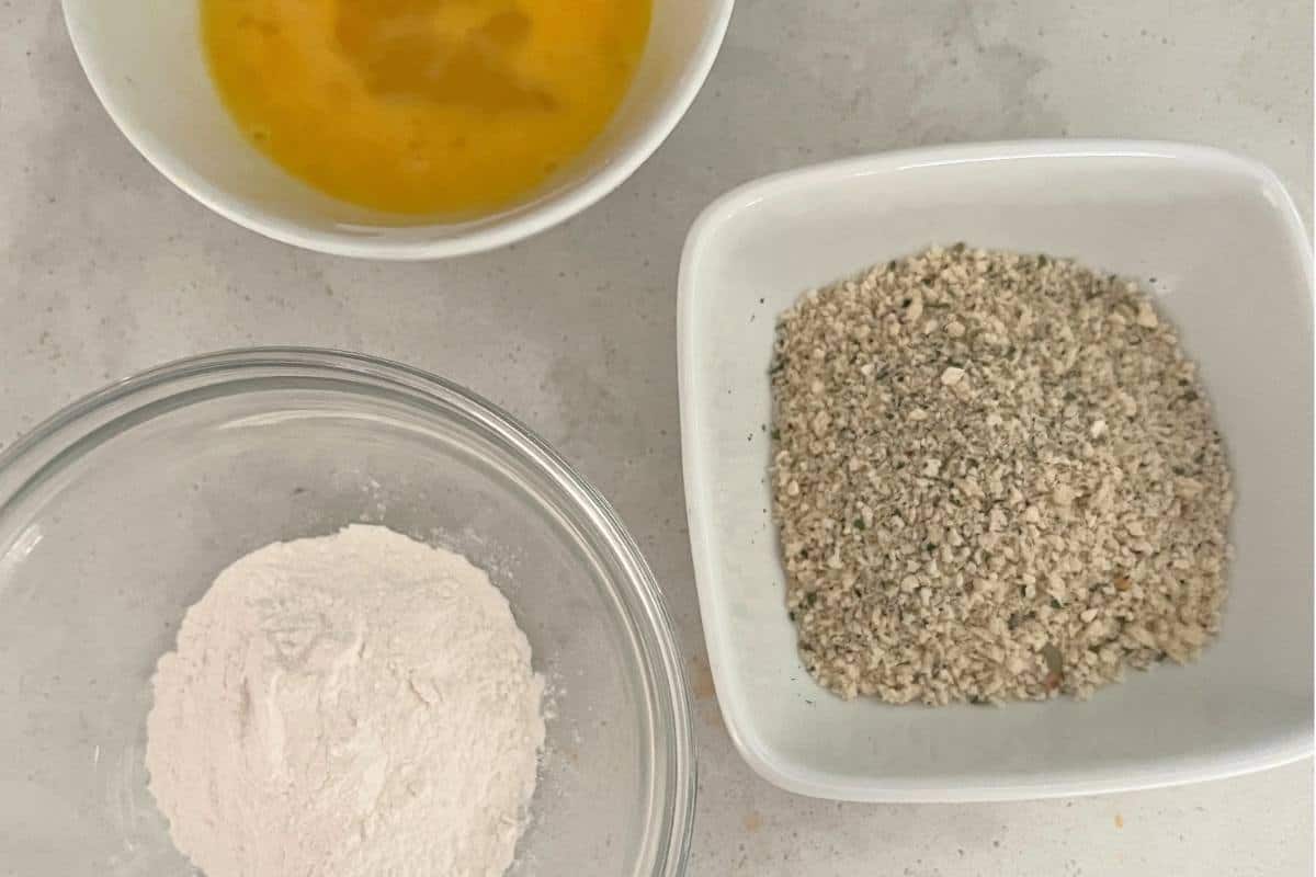 Flour, egg, and bread crumbs in a bowl.