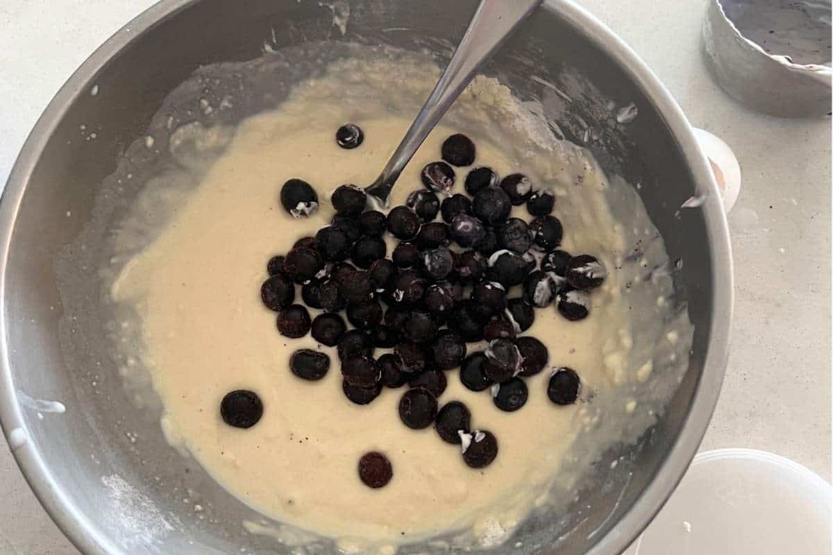 Wet and dry ingredients mixed together for blueberry muffins in a bowl.