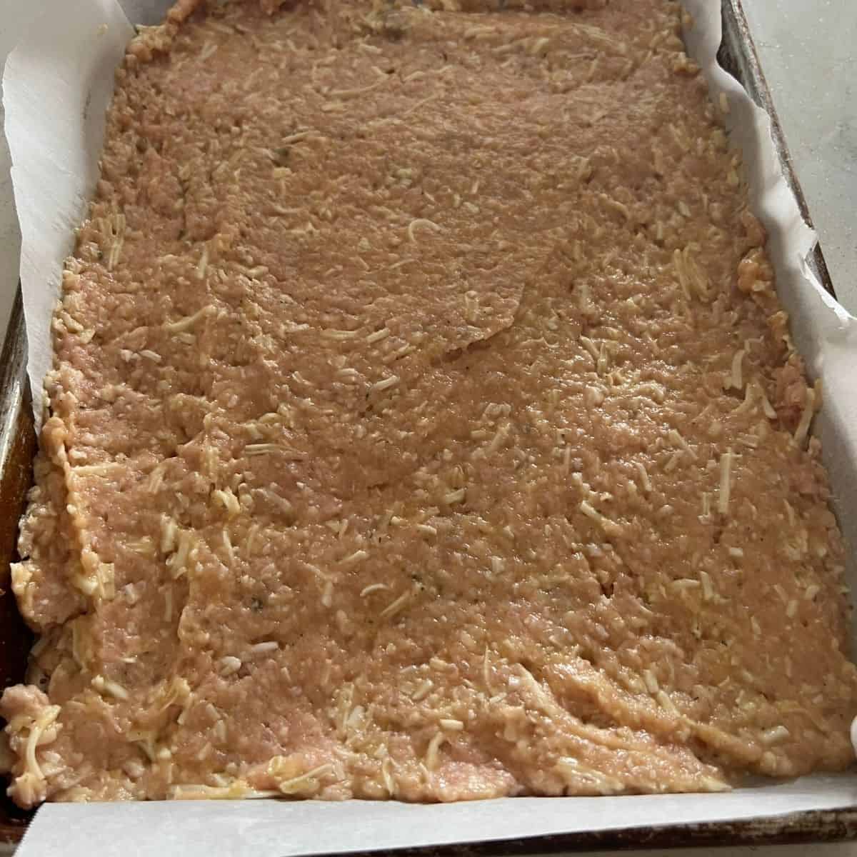 Carnivore pizza crust shaped out on a pan.