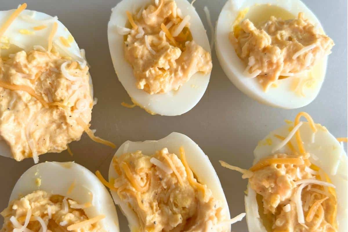 Finished deviled eggs topped with cheese.