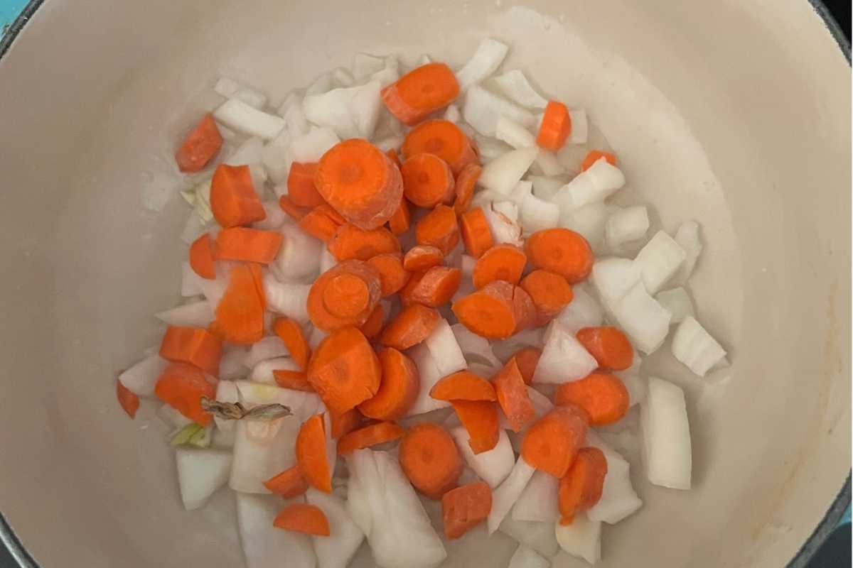 Carrots and onions cooking in pot.