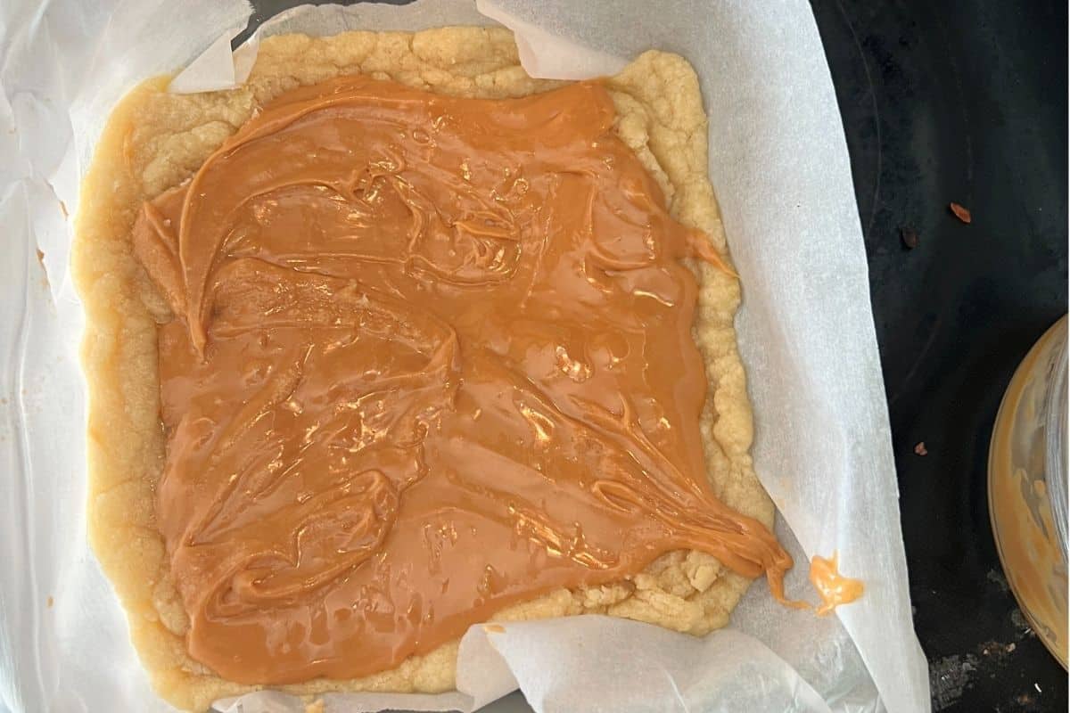 Caramel sauce spread over cookie bars.