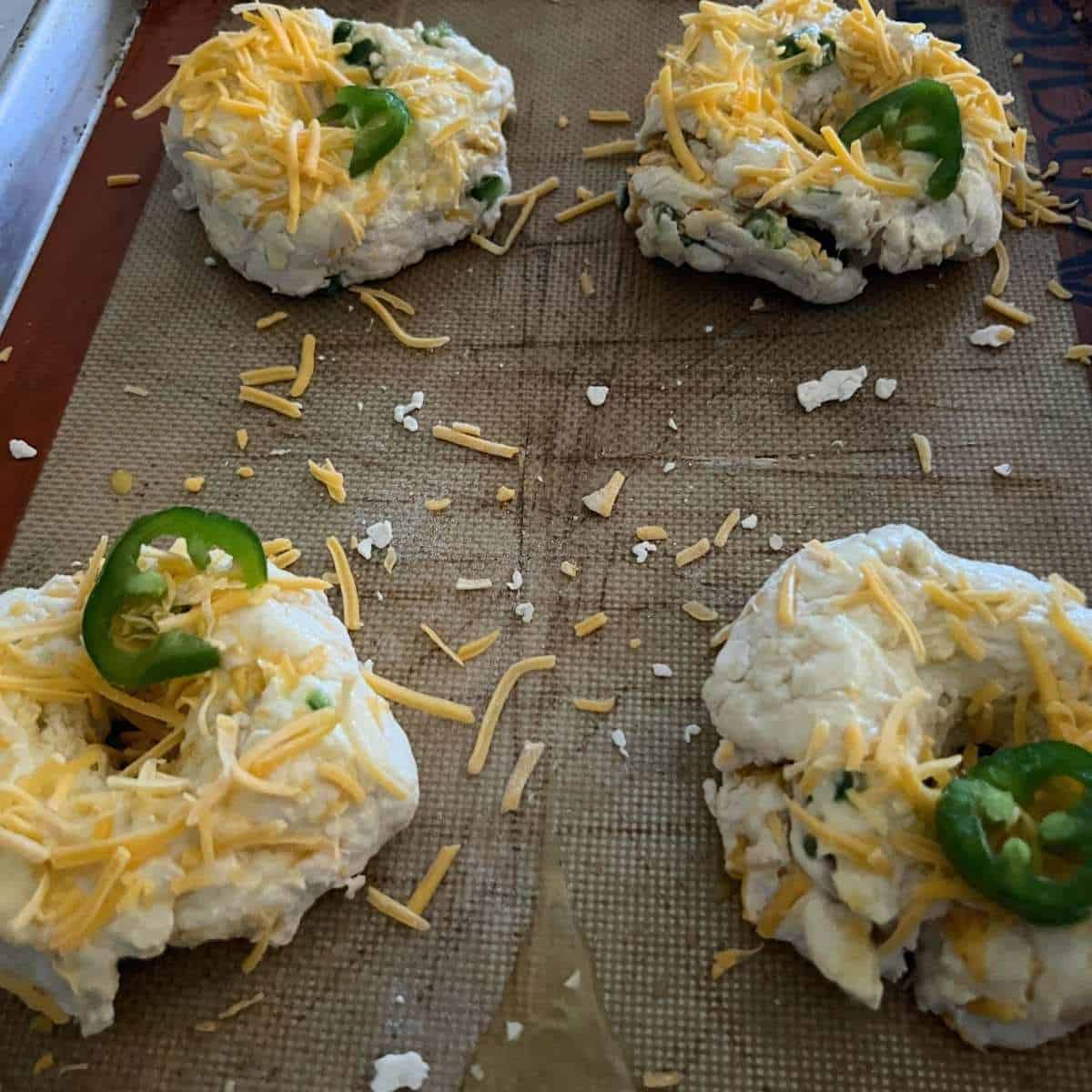 Shaped cheddar jalapeno bagels on a sheet pan.
