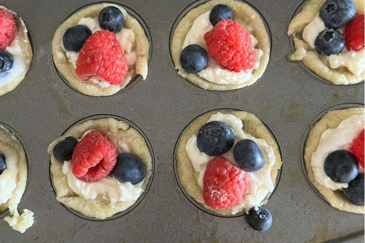 Finished fruit pizza cups topped with blueberries and raspberries.