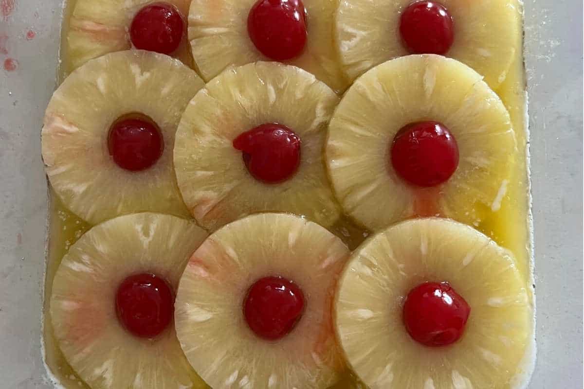 Pineapple and cherries lined up in a pan.