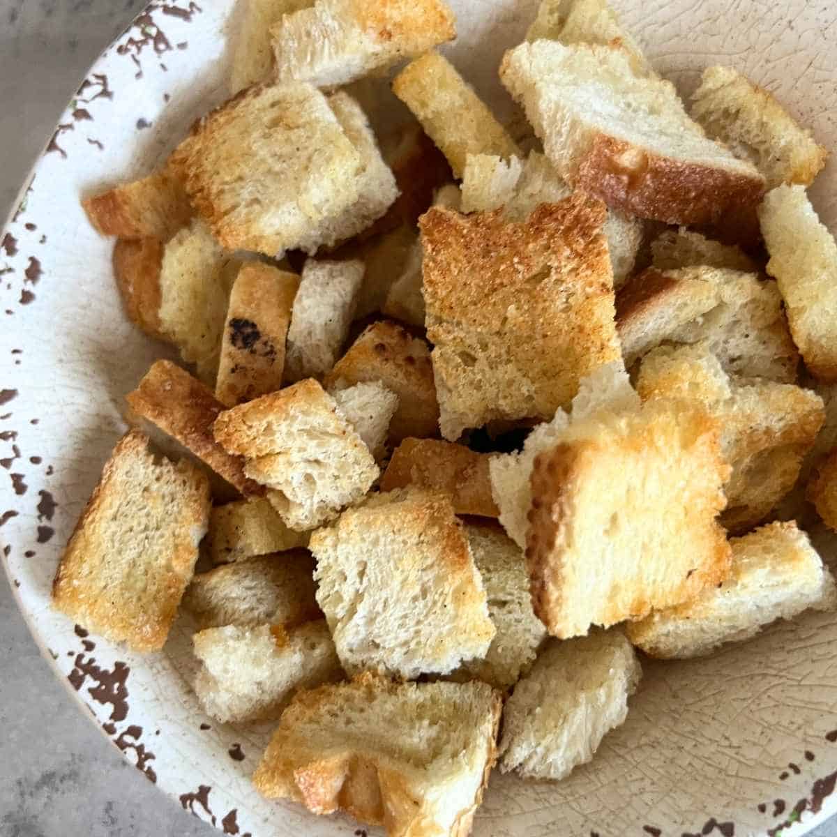 Cripsy air fryer croutons in a white bowl. 