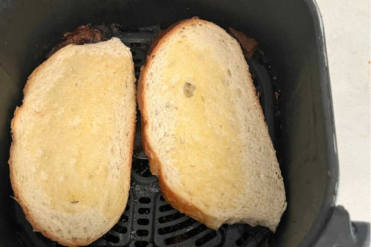 Buttered bread in an air fryer basket. 