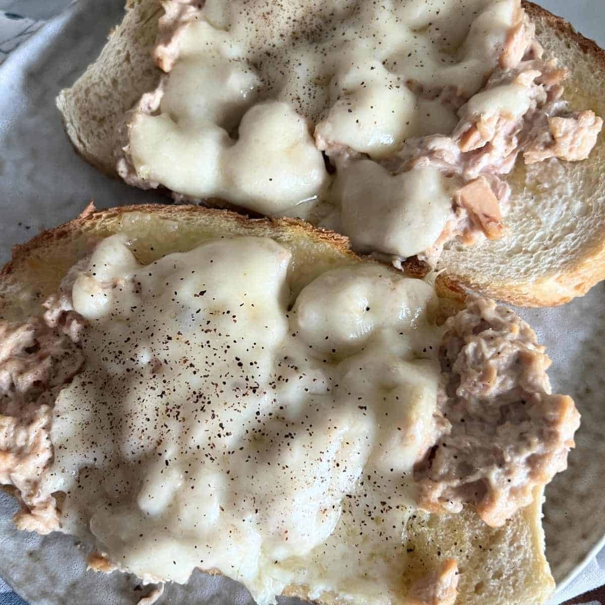 Melted swiss cheese on top of an air fryer tuna melt topped with freshly cracked black pepper. 