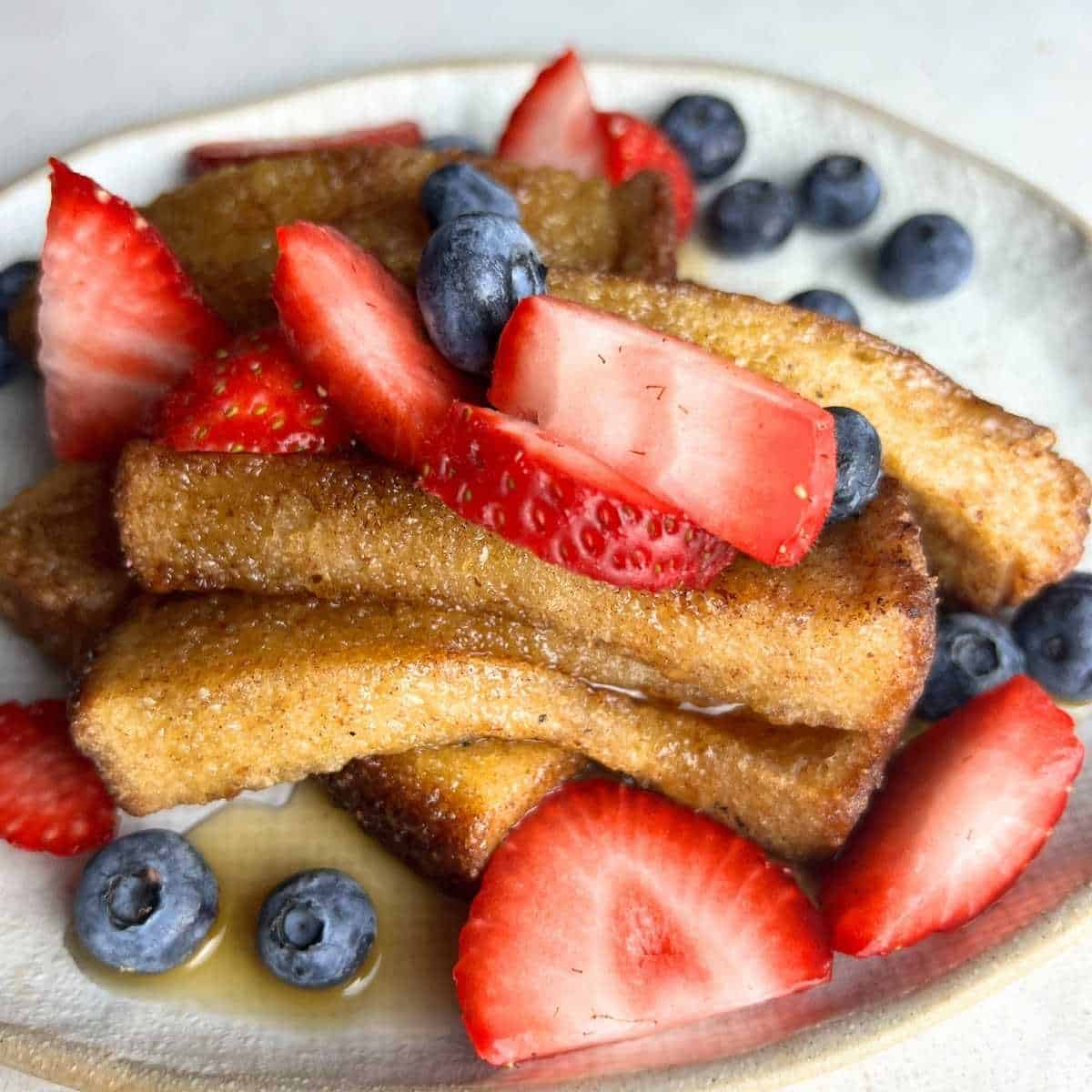 Frozen French toast sticks topped with maple syrup and mixed berries.