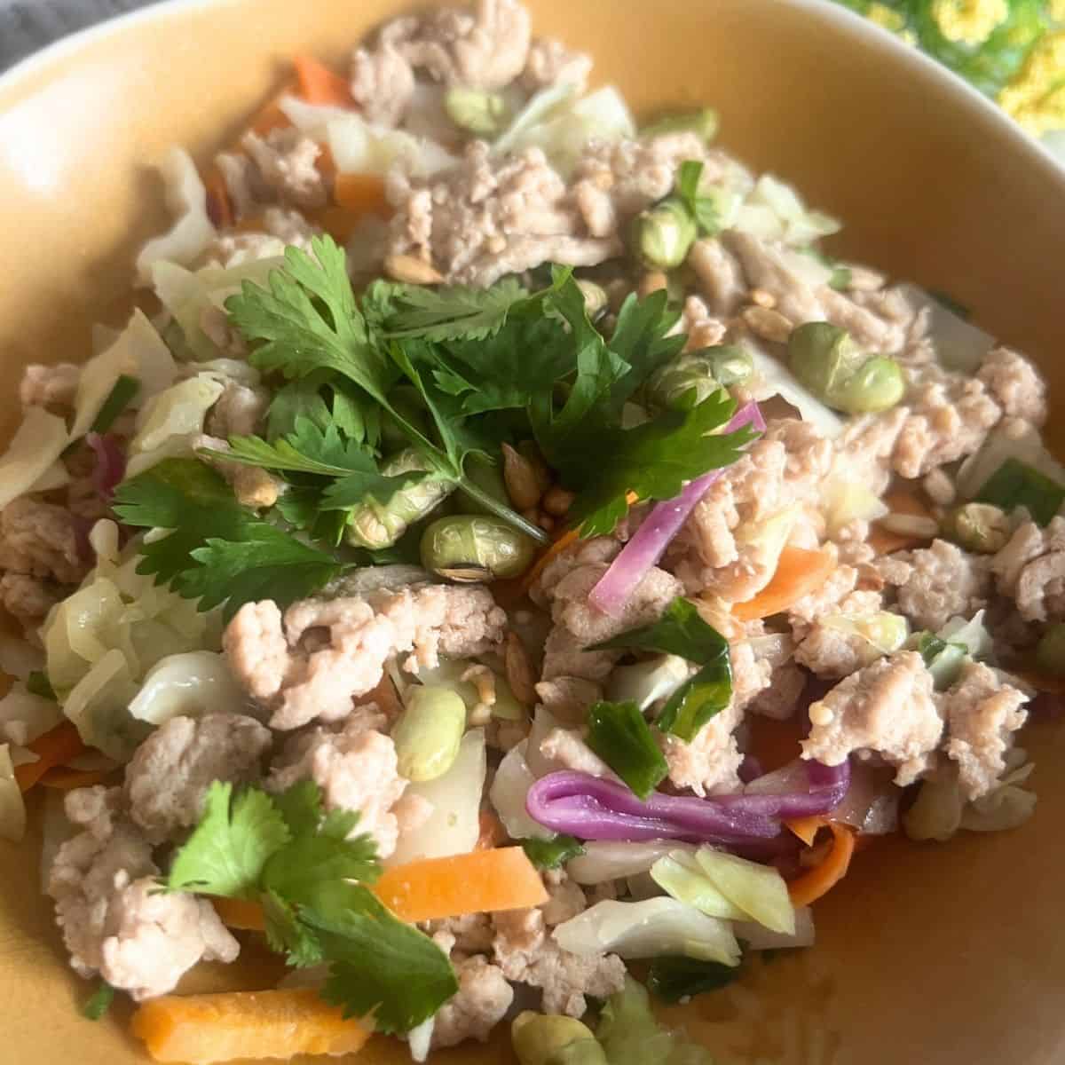 Chicken egg roll in a bowl topped with cilantro and nuts.