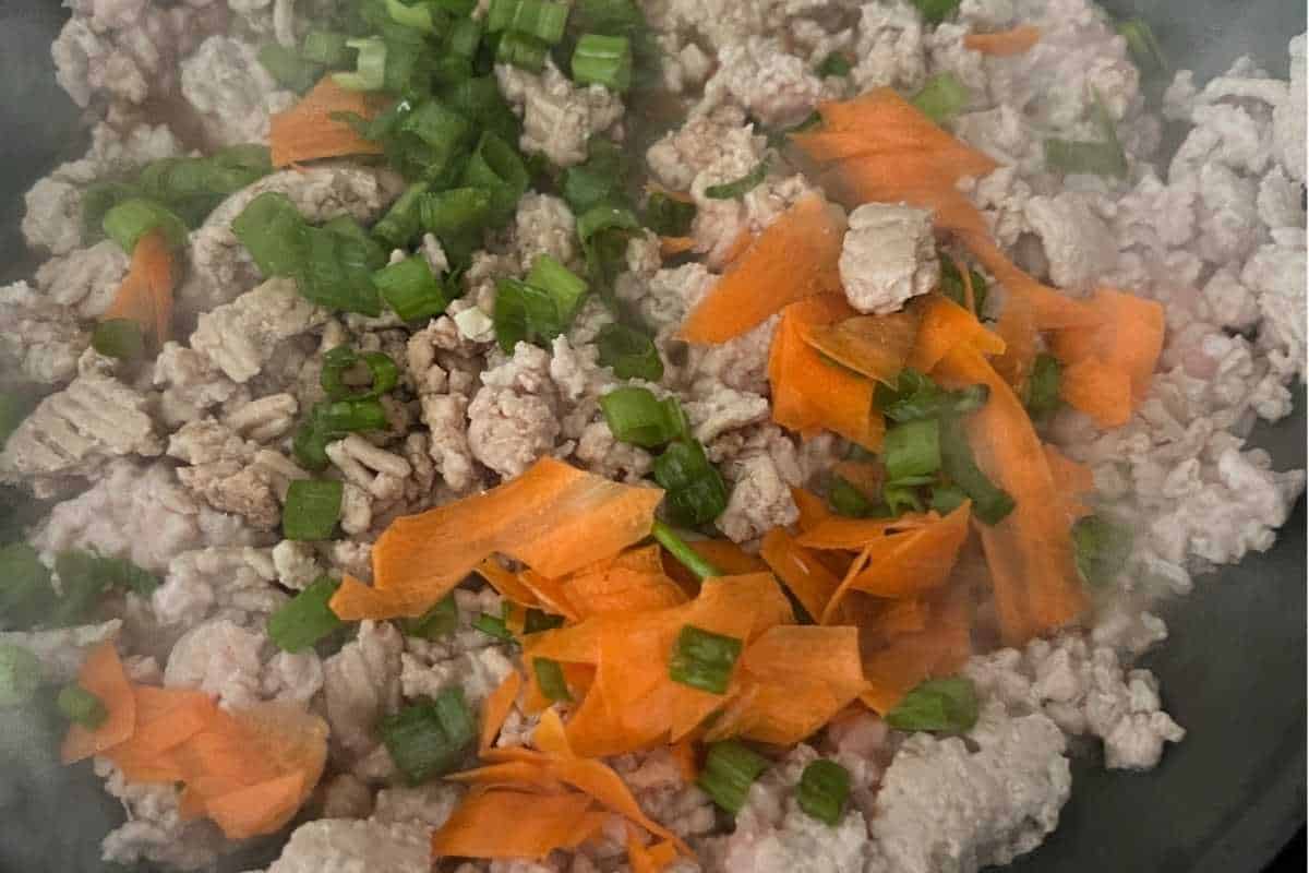 Aromatics and ground chicken cooking in a skillet.