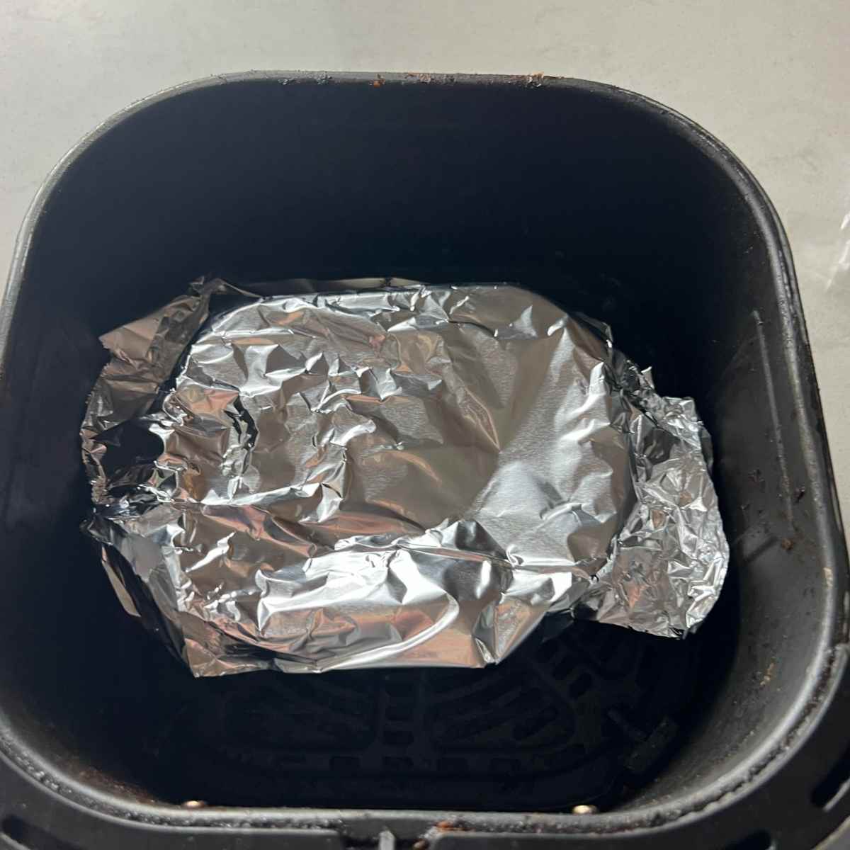 Foiled lasagna in air fryer basket. 