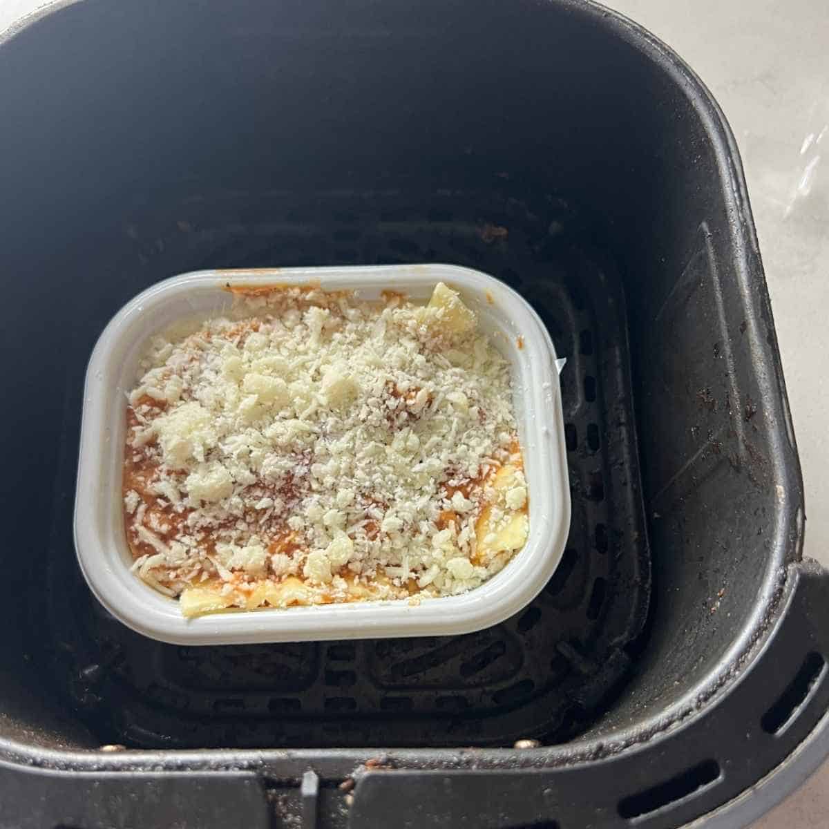 Frozen lasagna in air fryer basket. 