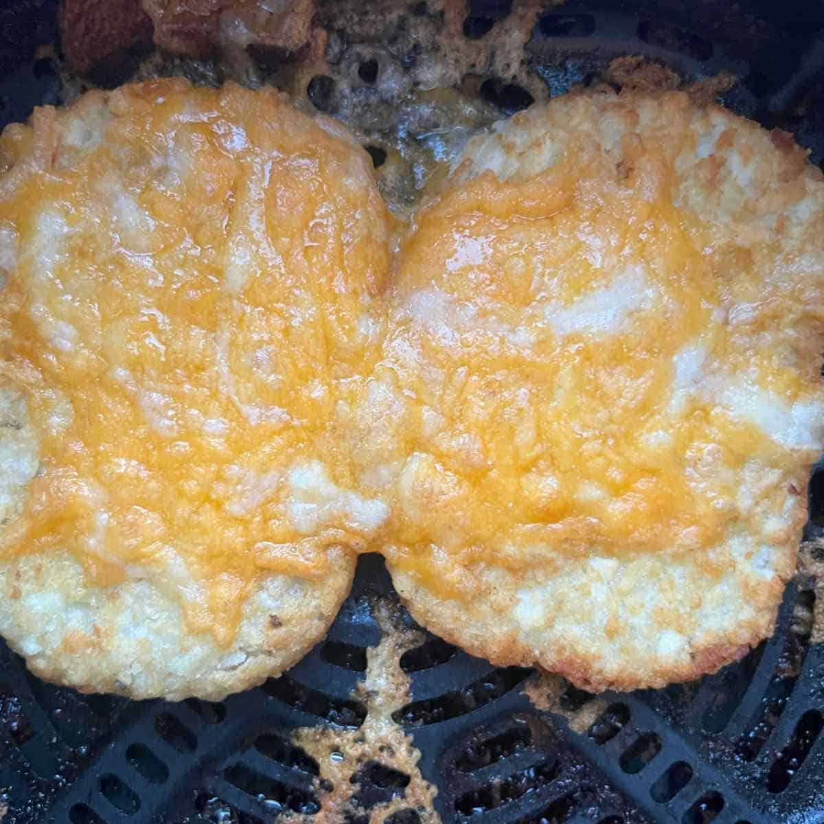 Hash Browns in air fryer topped with cheese.