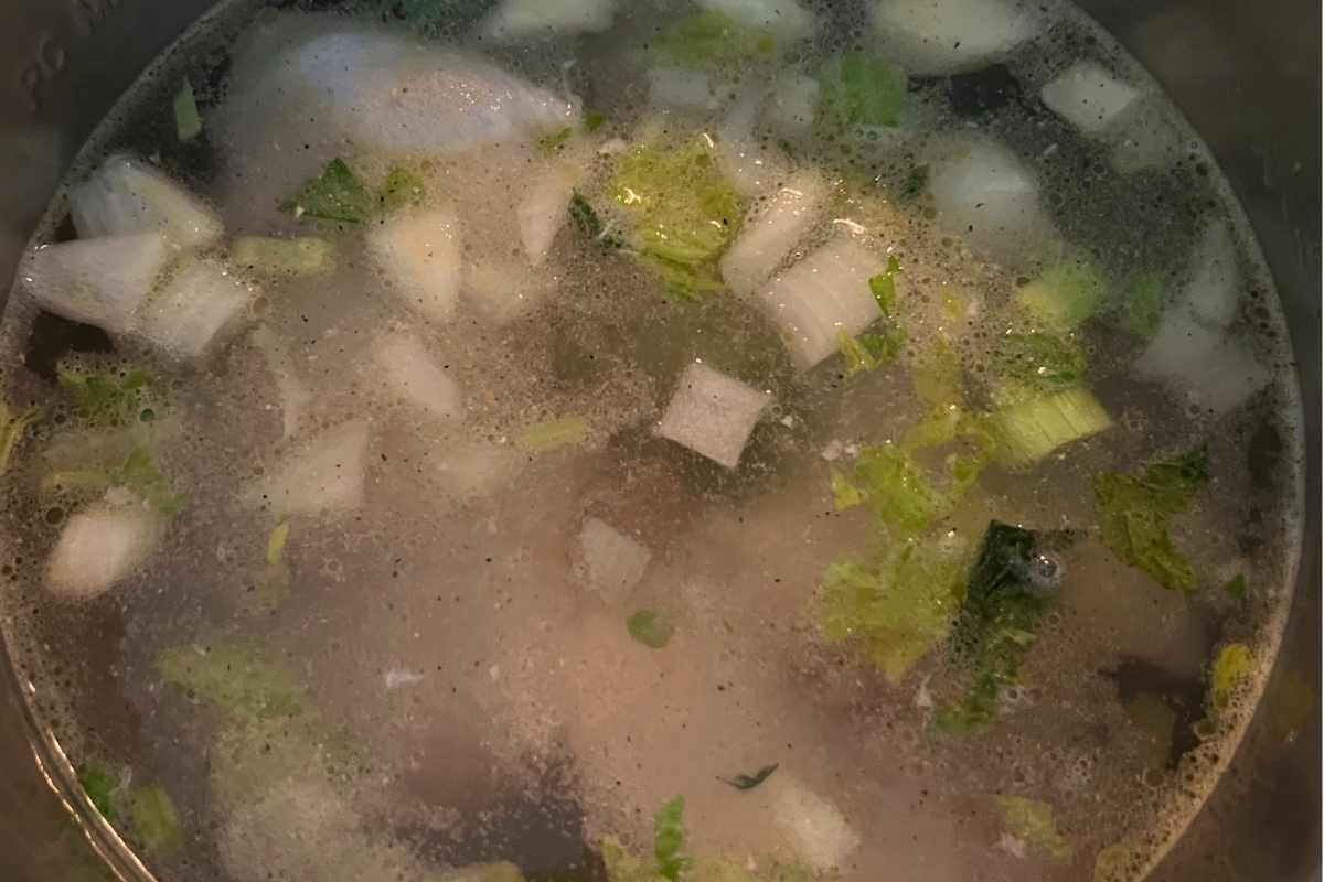 Chicken and vegetables simmering in a stock pot.