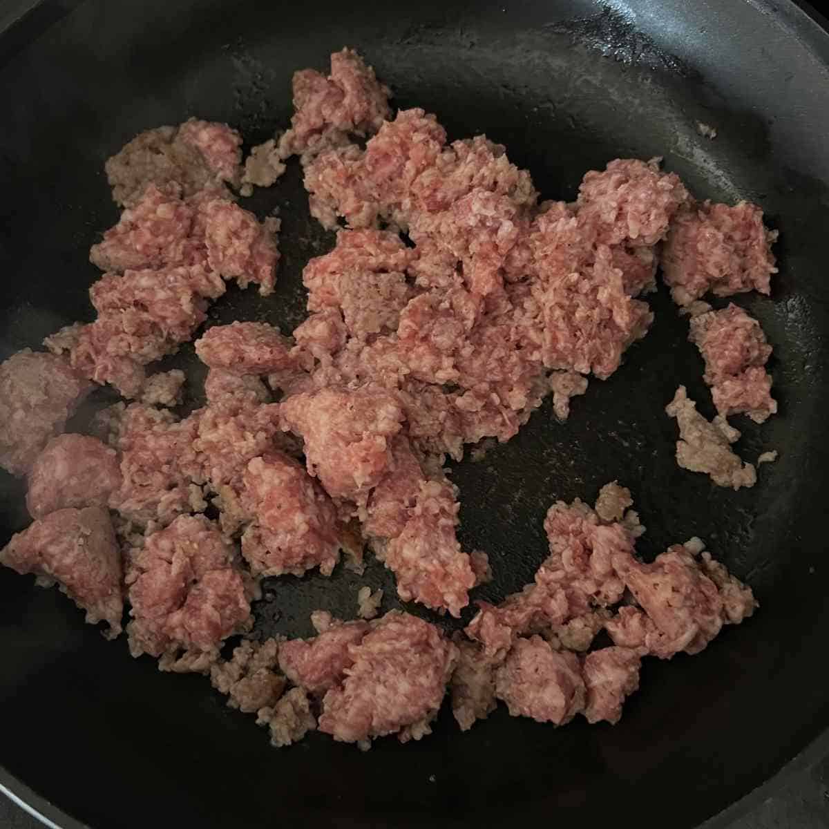Pork sauge cooking in a skillet. 