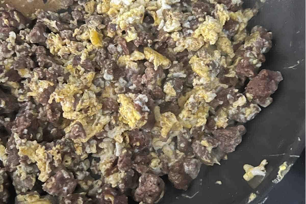 Scrambled eggs and ground beef in a pan.