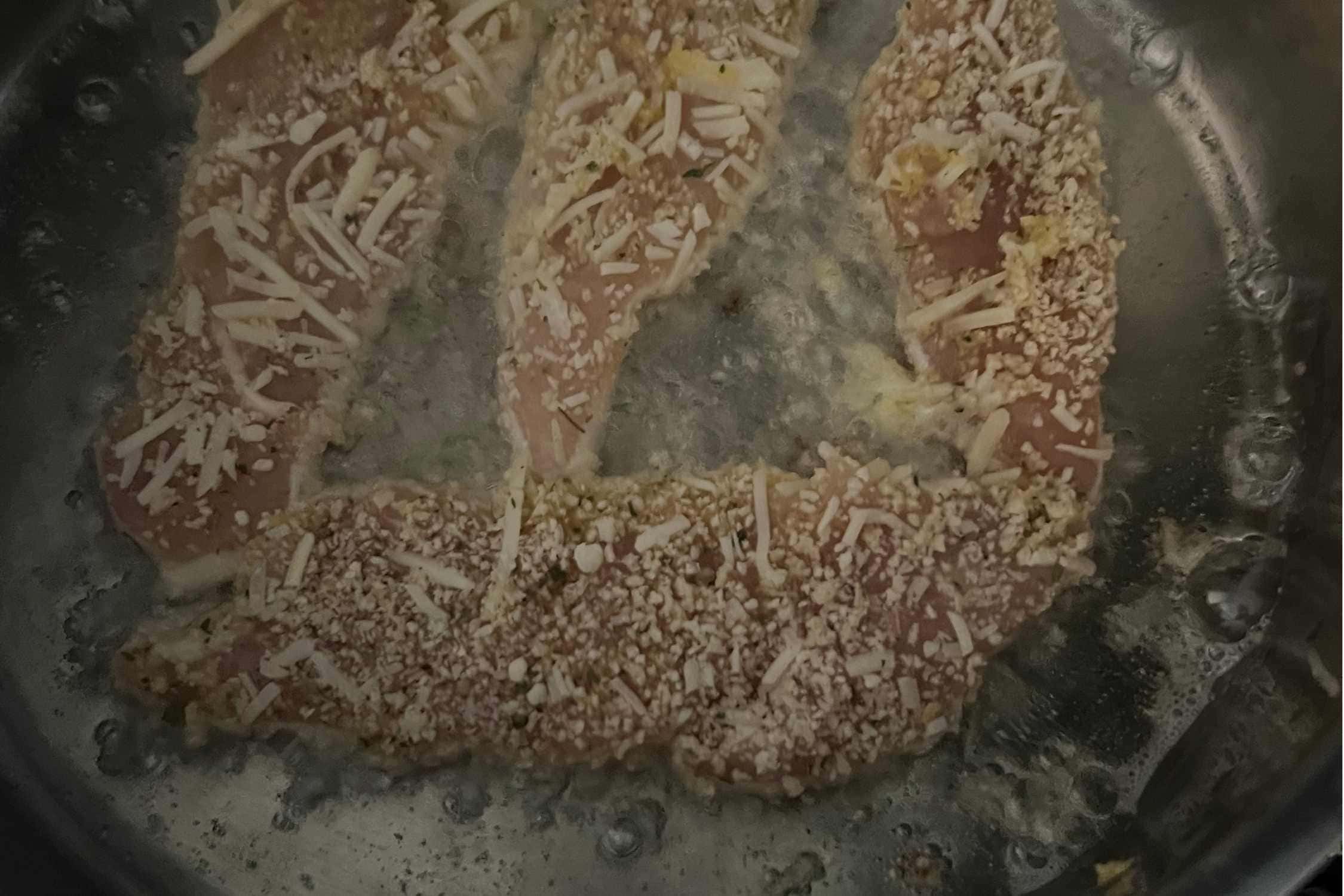 Chicken cutlets pan frying in a skillet. 