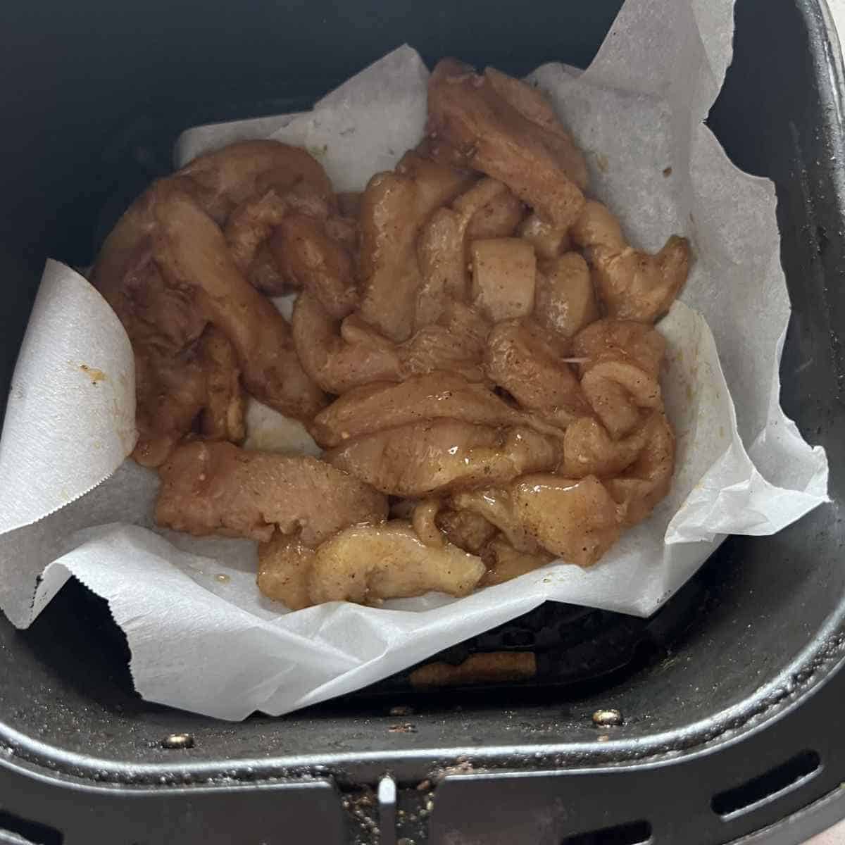 Seasoned air fryer chicken in an air fryer basket. 