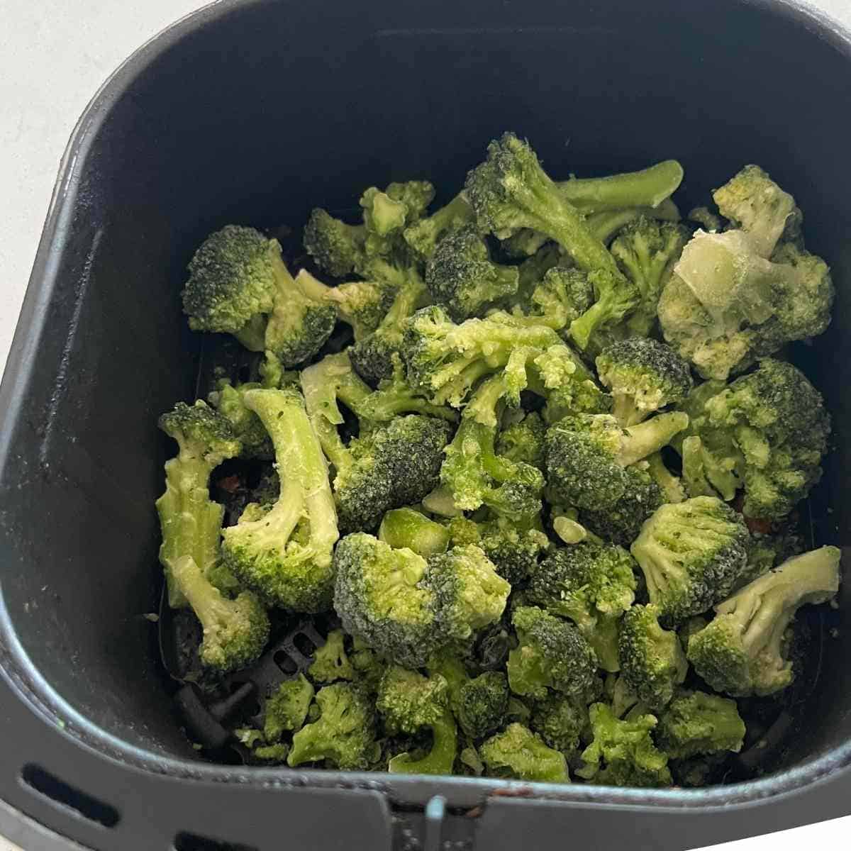 Frozen brococli in air fryer basket.