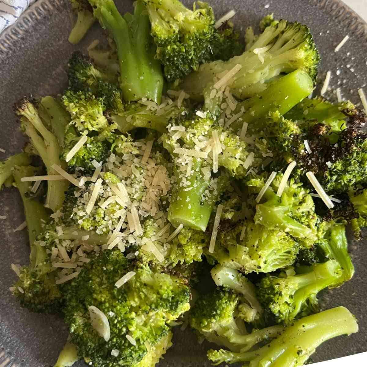 Air fryer finished frozen broccoli topped with some parmesan cheese and pepper.