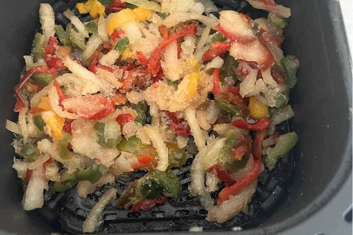 Air fried pepper and onions in an air fryer basket. 