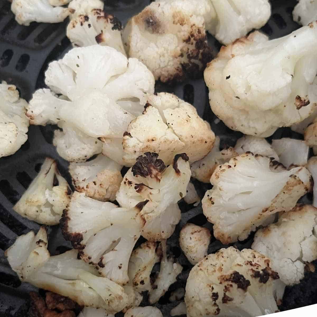 Cooked cauliflower in air fryer basket.