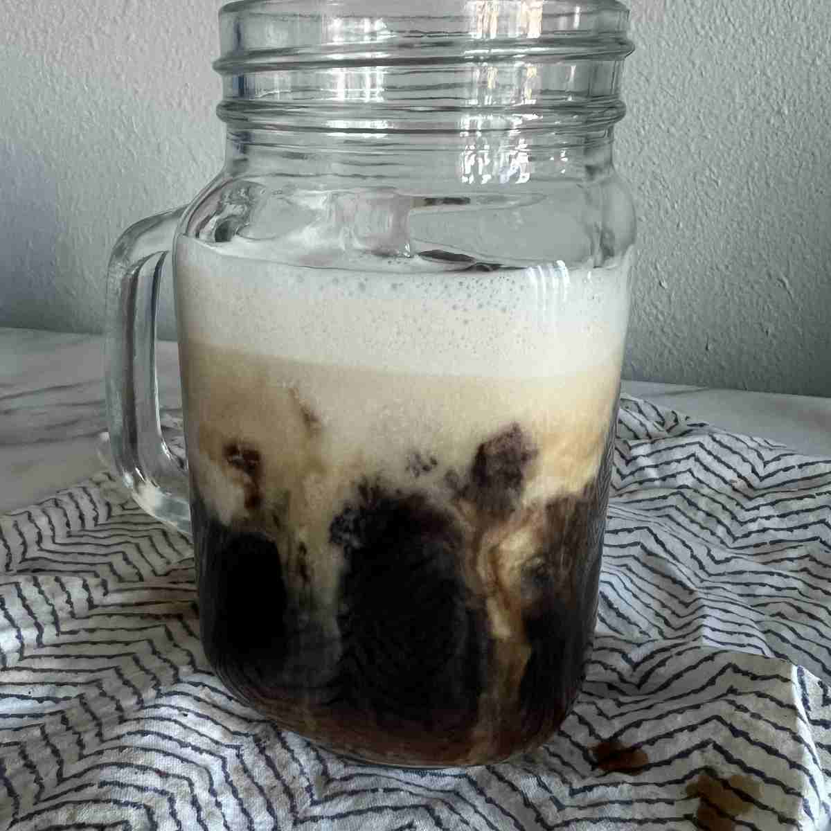 Banana milk latte with ice in a tall glass.