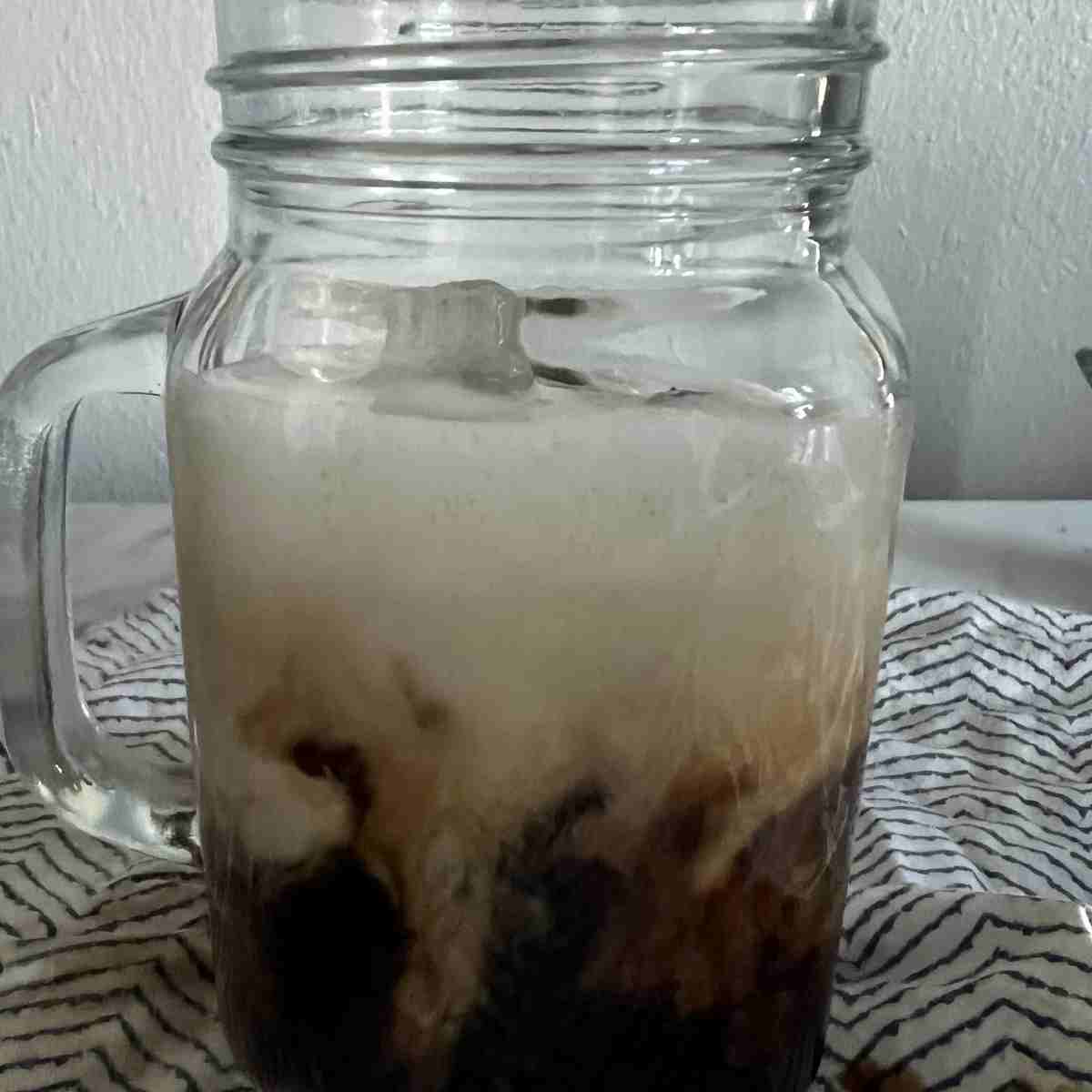 Banana milk latte in a tall glass.