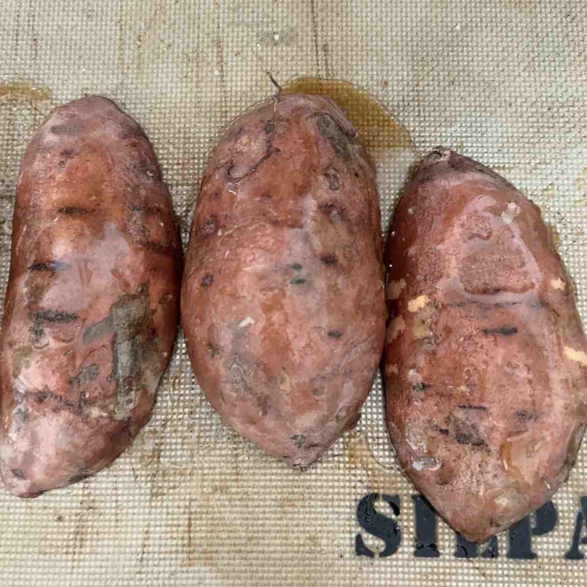 Sweet potatoes placed cut side down on a sheet pan.