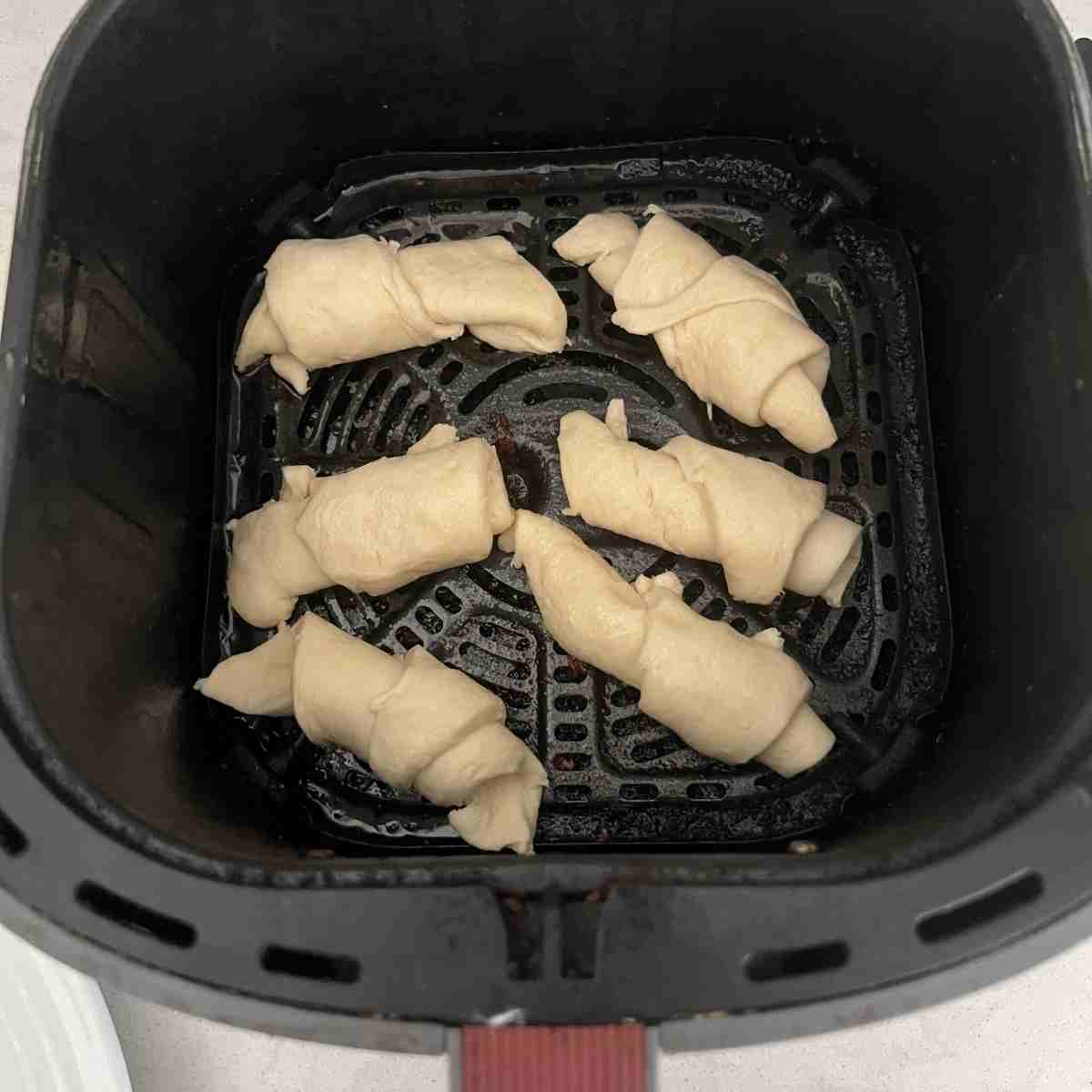 Crescent rolls in air fryer basket. 