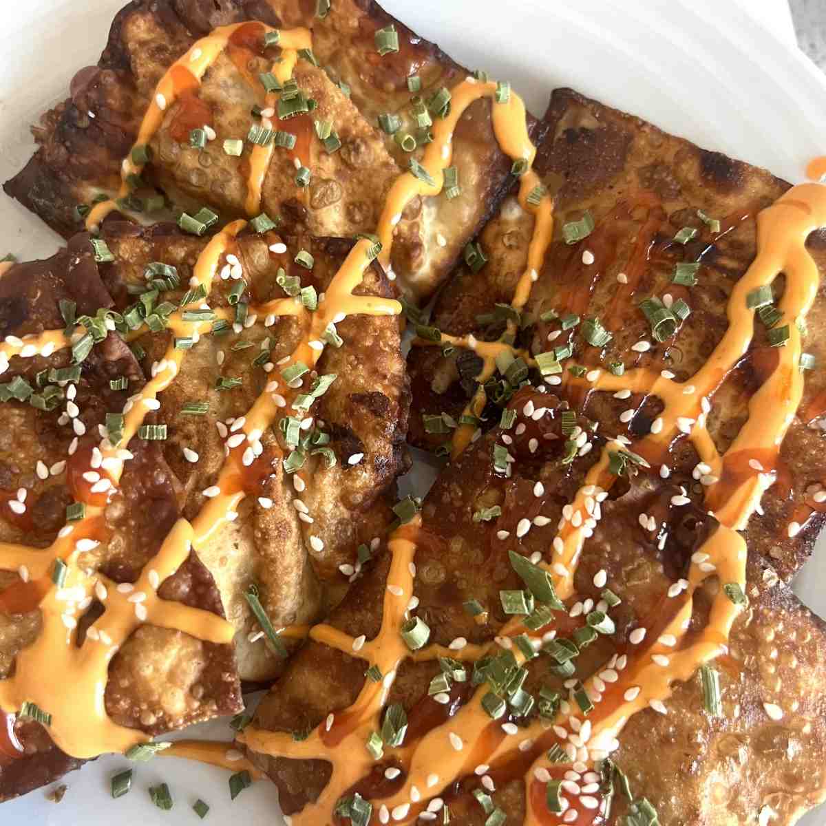 Crab rangoon nachos topped with spicy mayo and chili sauce.