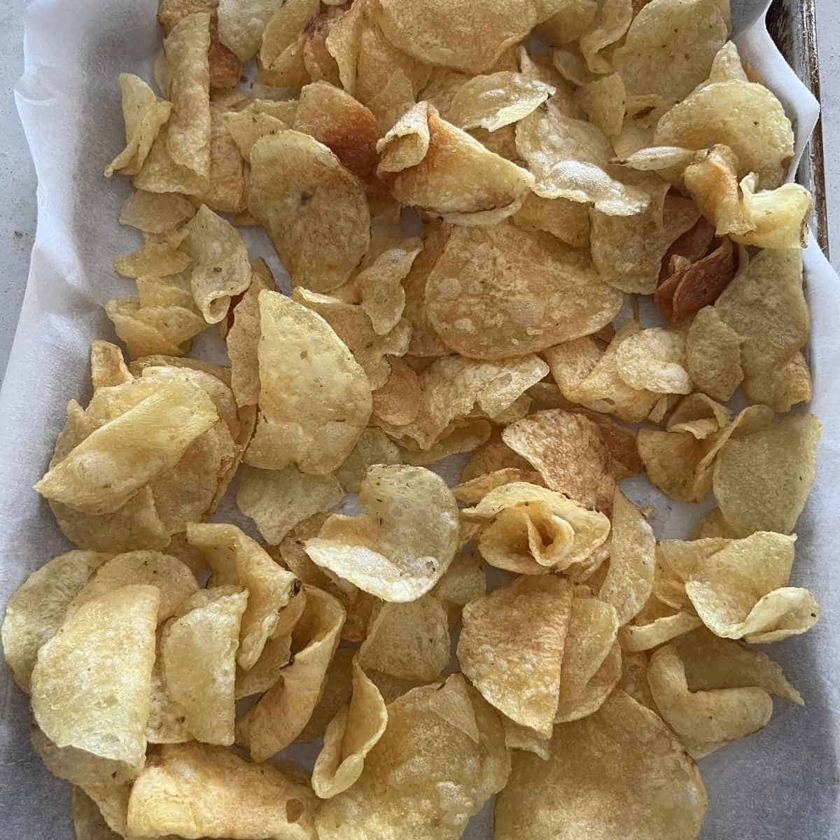 Kettle chips spread out on a pan. 
