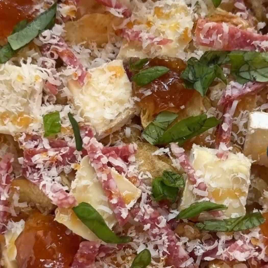 Charcuterie nachos topped with brie and salami.