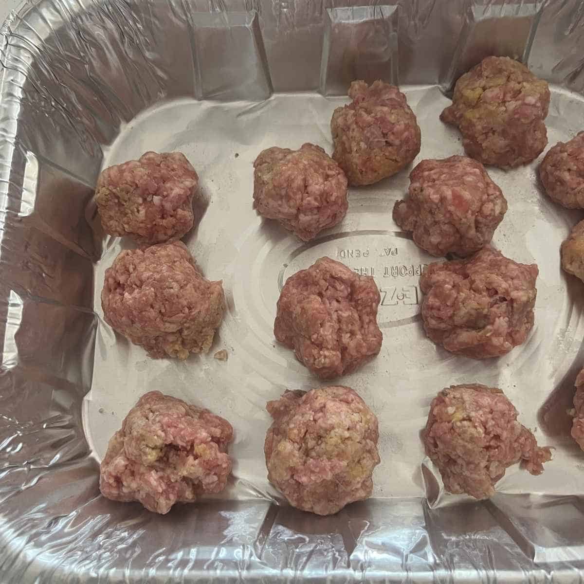 Rolled smoked meatballs in a tinfoil container for smoker.