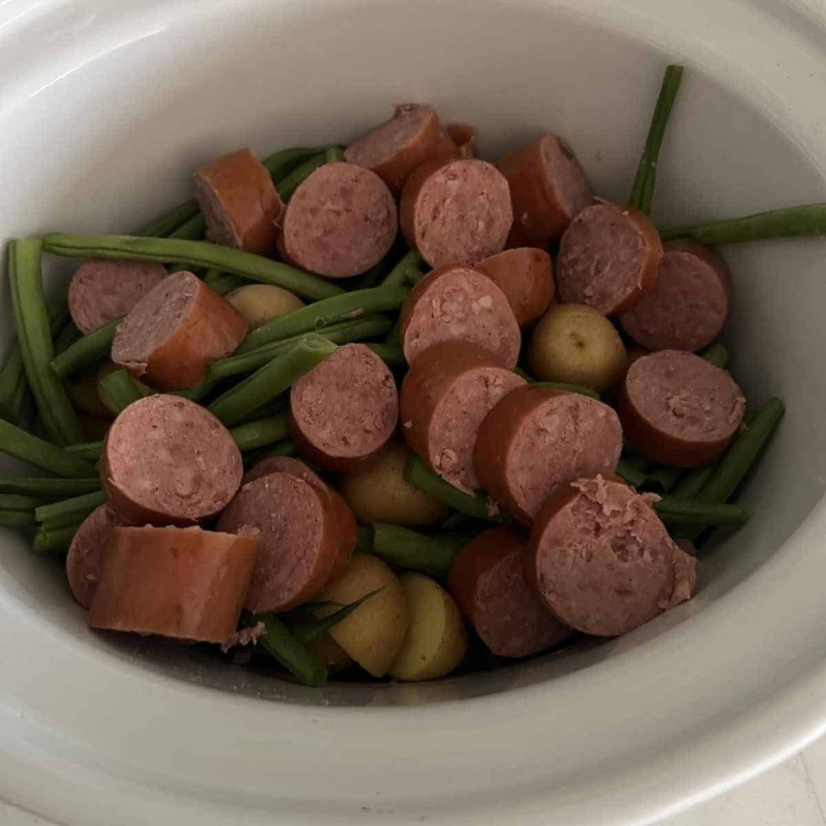 Potatoes, green beans, and sausage in slow cooker.