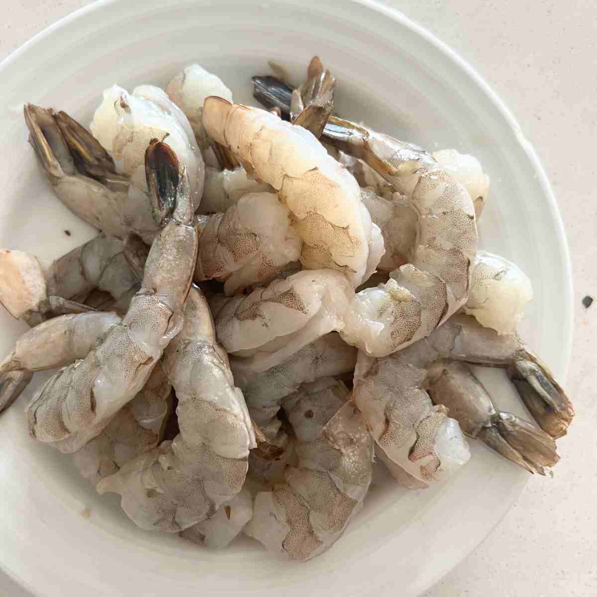 Raw shrimp on a white plate.